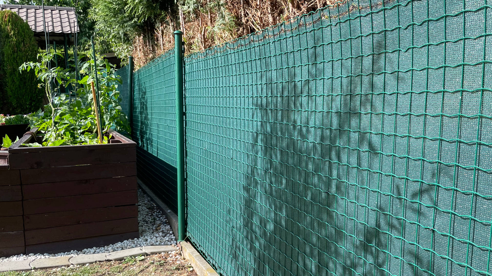 Zelená stínící tkanina, zastínění 90 %, gramáž 180 g/m². Instalována na plot ze svařovaného pletiva.