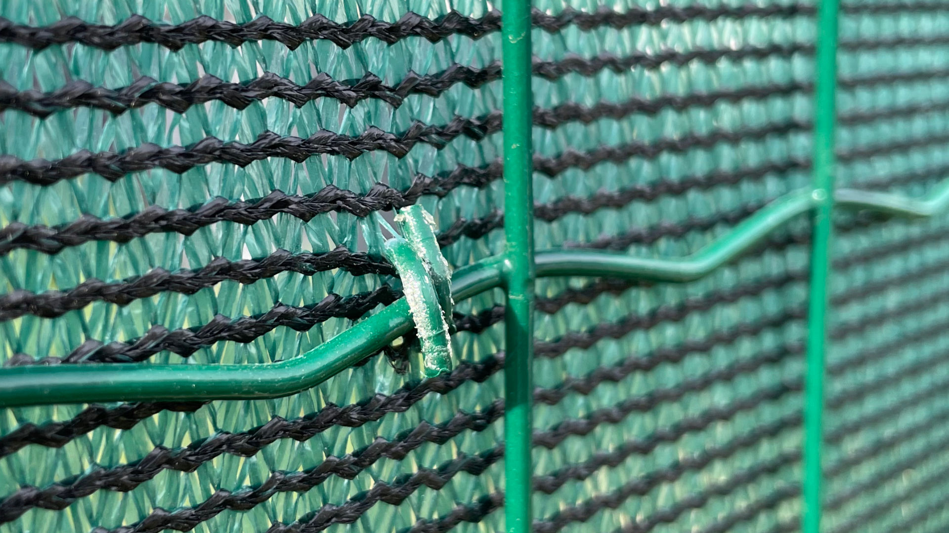 Zelená stínící tkanina, zastínění 90 %, gramáž 180 g/m². Detail uchycení tkaniny pomocí spon Rocafix.