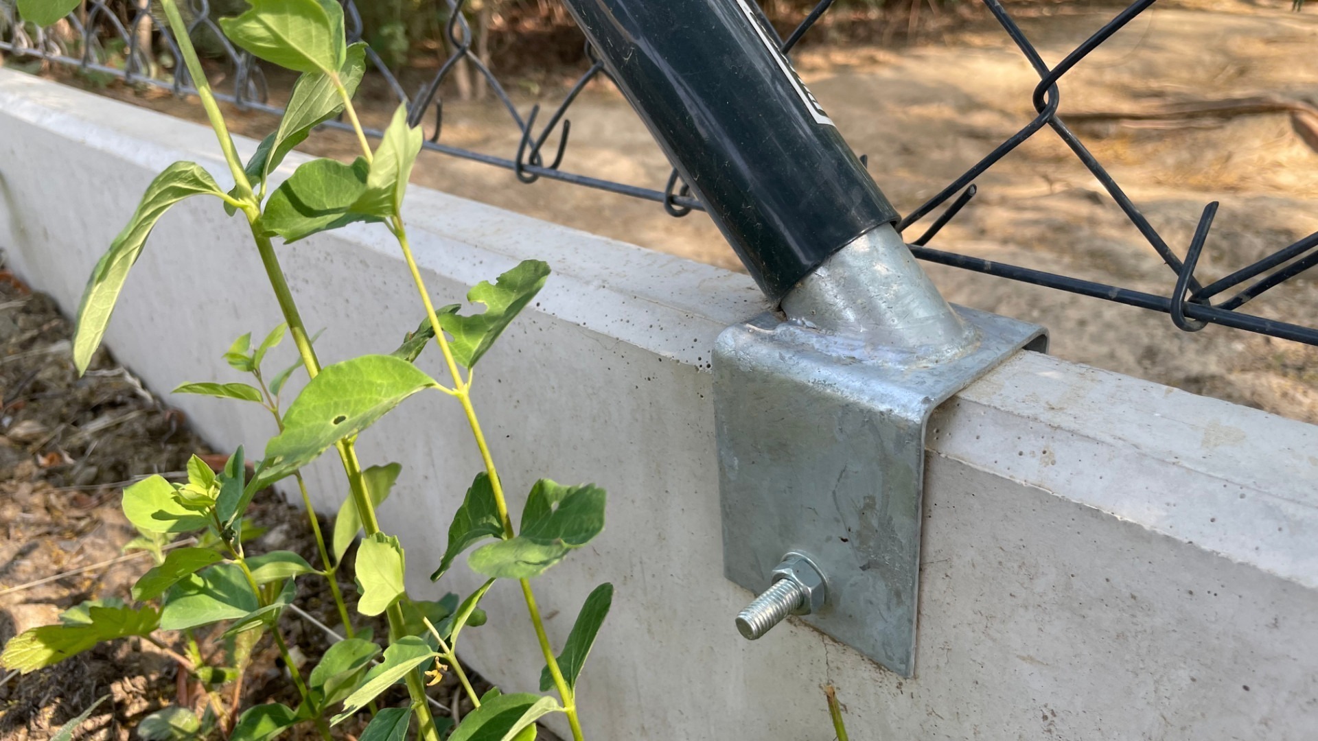 Podhrabová betonová deska pod plot jako náhrada podezdívky – detail uchycení držáku na plotovou vzpěru.