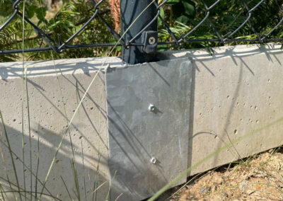 Podhrabová betonová deska pod plot jako náhrada podezdívky – detail uchycení desky v průběžném držáku.