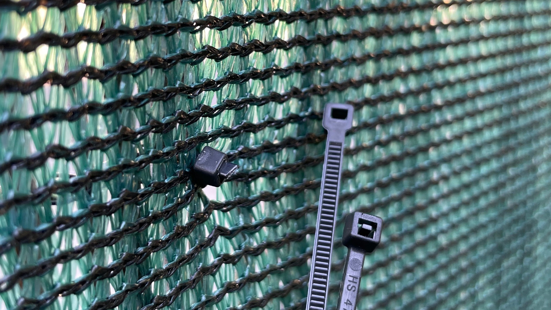 Detail uchycení stínící tkaniny pomocí stahovacích plastových pásek (bindrů).
